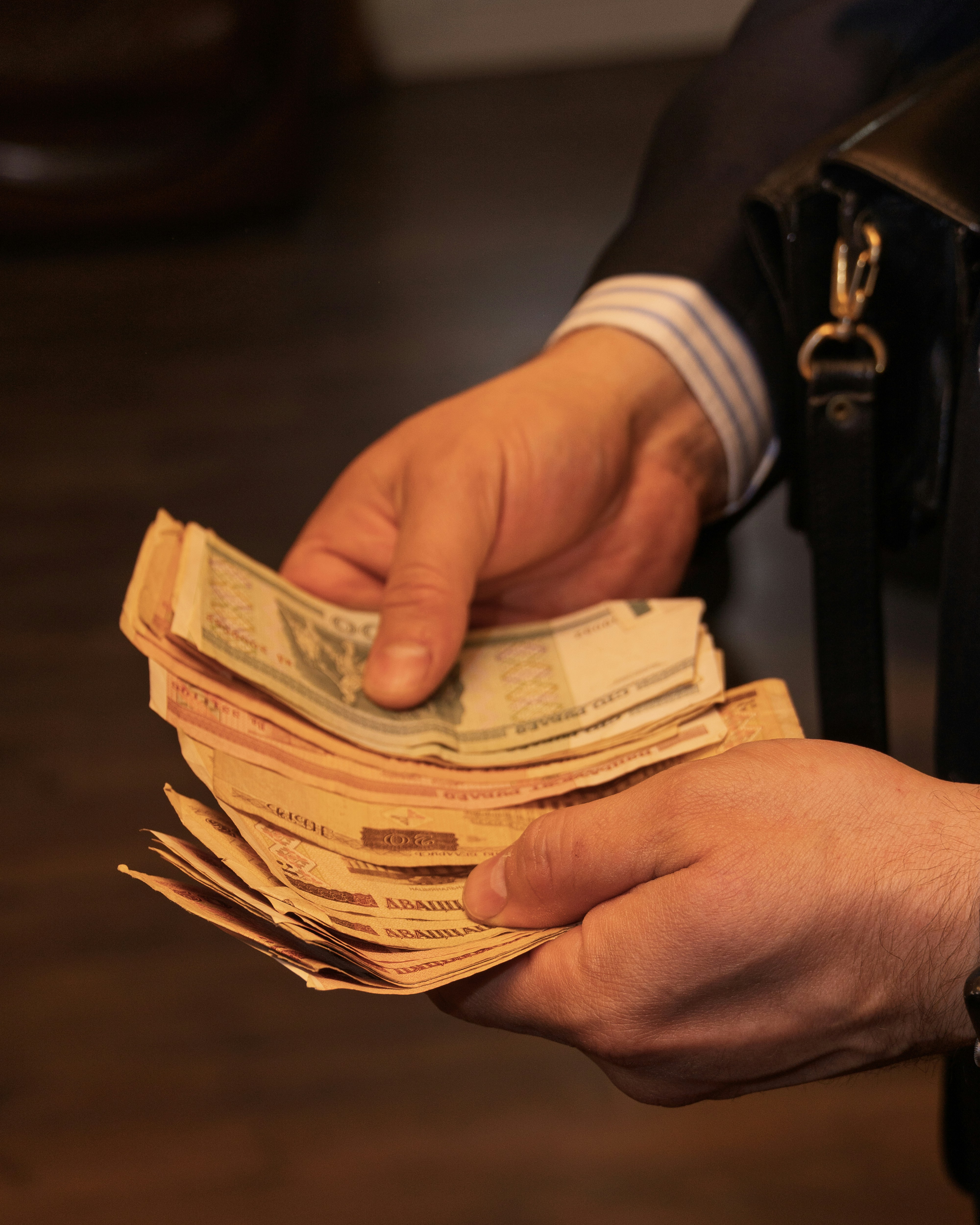 Hands holding a stack of assorted banknotes